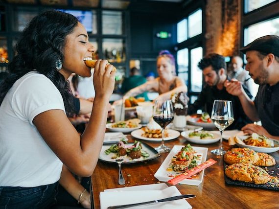 group of young adults eating food at a restaurant